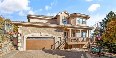 Modern two-story house with stone and wood exterior, attached garage, and a basketball hoop.