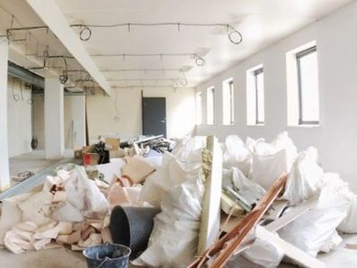 Renovation debris and construction materials piled in a bright, unfinished room.
