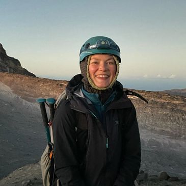Woman smiling outdoors with hiking gear on.
