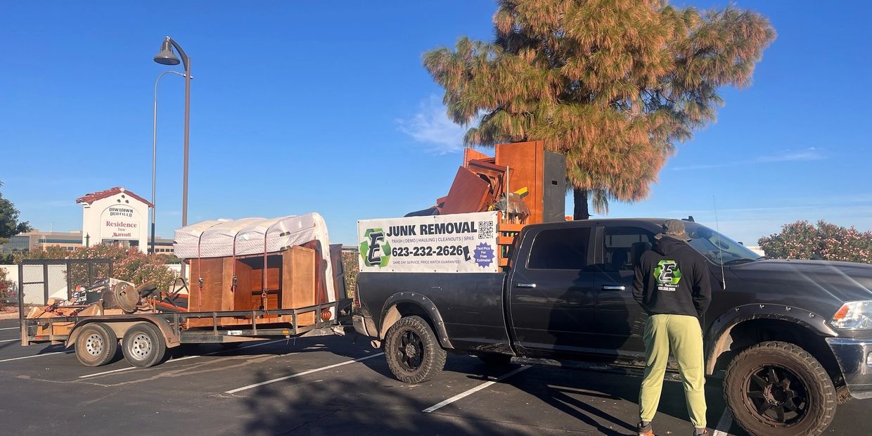 Pickup truck with junk removal sign and loaded trailer.