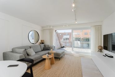 Bright modern living room with gray sofa and large window to balcony.
