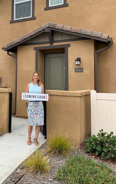 Summer Knight in front of a townhome holding a sign that says "Coming Soon"