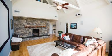 The family room of a home with vaulted ceilings, a sectional couch and a stone fireplace.