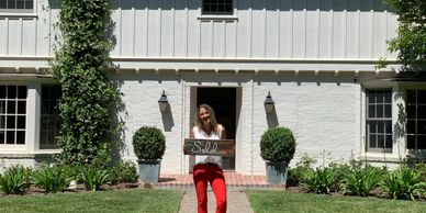 Summer holding a "sold" sign in front of a home in Hope Ranch.