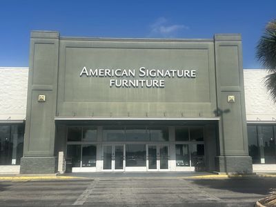 Storefront of American Signature Furniture under clear blue sky.