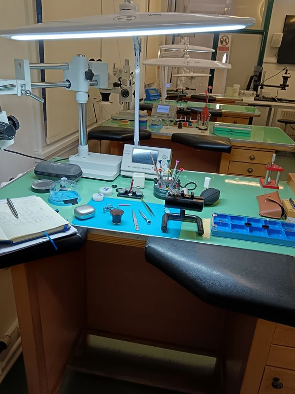 Watchmaking workspace with tools and equipment.