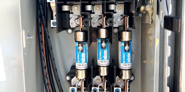 Three blue electrical fuses inside a metal fuse box.