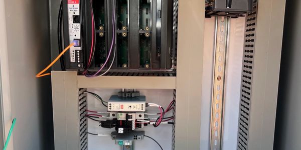Electrical panel with circuit boards and wiring inside a metal enclosure.