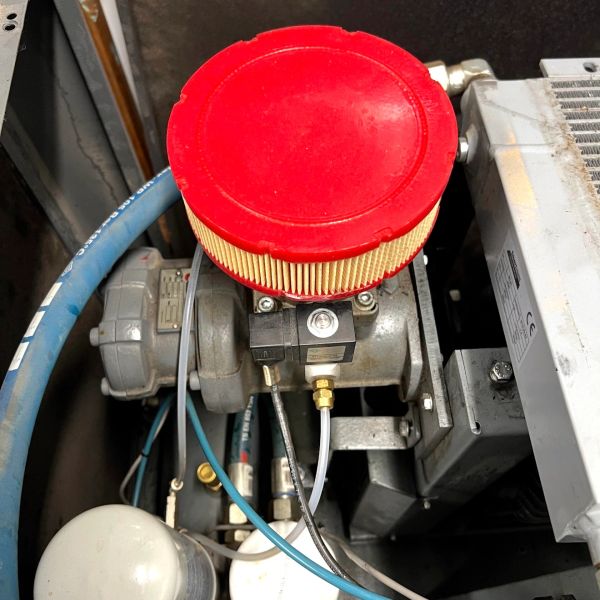Close-up of a mechanical component with a red air filter and connected hoses.