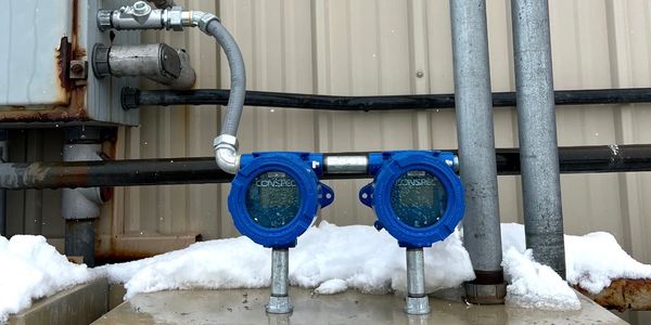 Two blue industrial meters installed outdoors with snow around.