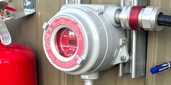 Close-up of a gas meter with a red fire extinguisher nearby.