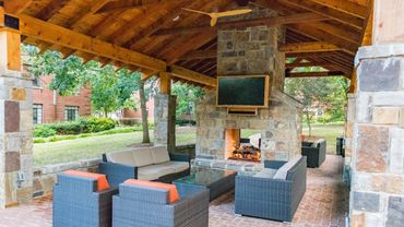 Outdoor covered patio with fireplace and comfortable seating area.