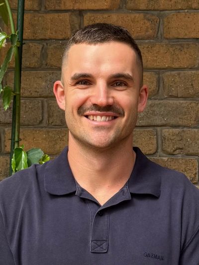 Smiling man with a mustache wearing a navy blue polo shirt.