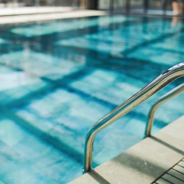 Close-up of a pool ladder leading into a clear swimming pool.