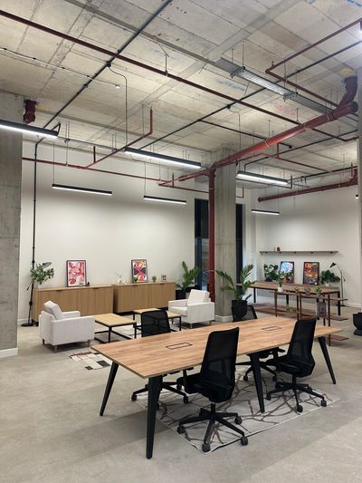 Modern coworking space with wooden desks and black chairs.