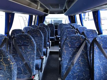 Interior of an empty blue-patterned seat coach bus with seatbelts.