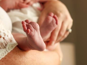 Close-up of a newborn baby's feet held gently by an adult.