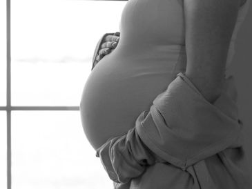 Close-up of a pregnant belly with hands gently holding it.
