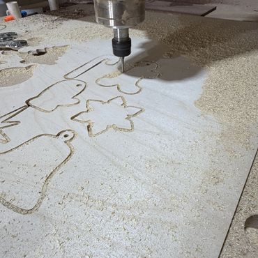CNC machine carving holiday shapes into wood.