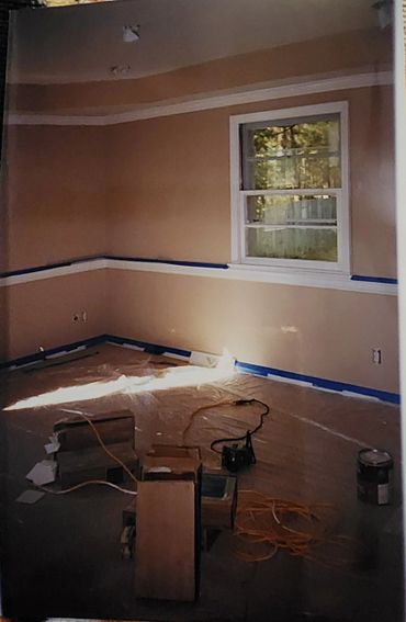 Room under renovation with taped walls and floor protection.