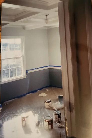 Room in the midst of a two-tone paint job with supplies on the floor.