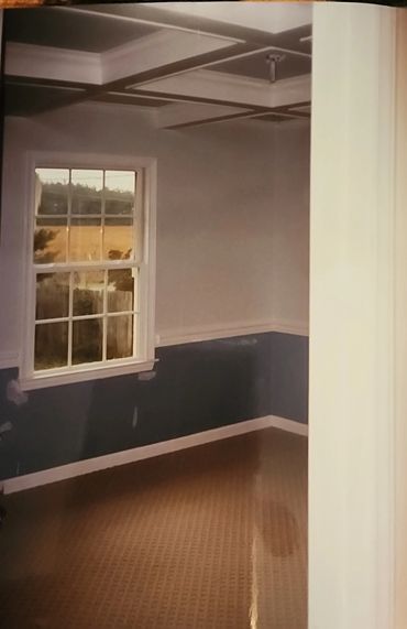 Empty room with a large window and coffered ceiling.