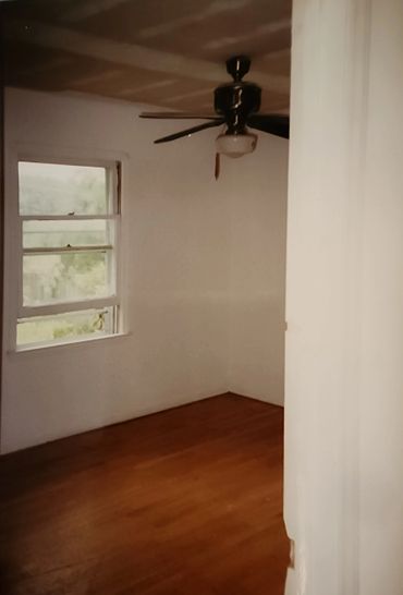 Empty room with wooden floor and ceiling fan.