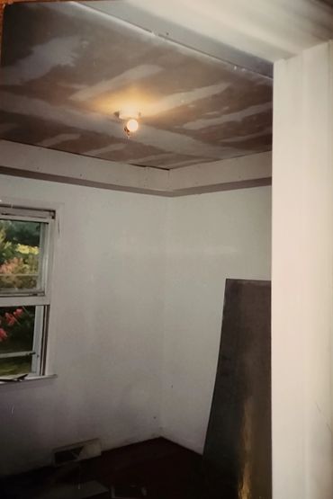 Room under renovation with unfinished ceiling and single light bulb.