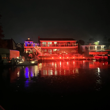 A house and dock lit up with red lights reflecting on water at night.