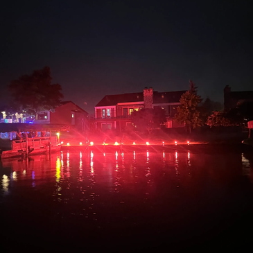 Red lights illuminate a waterfront dock at night.
