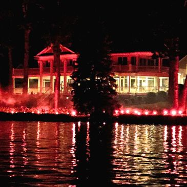 A house illuminated with red lights reflected in the water at night.