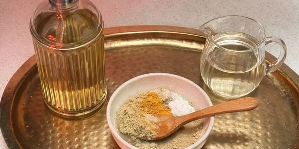 A brass tray holds a bowl of spices, a glass pitcher of water, and a bottle of oil.