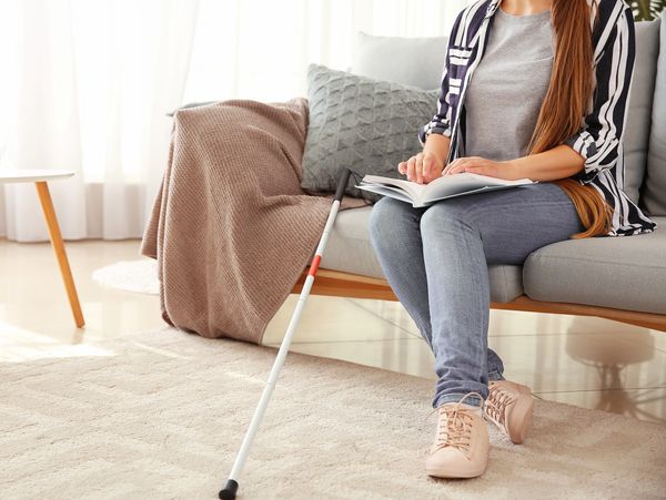 A visually impaired person sitting on a couch reading