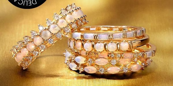 Elegant gold rings with opal and diamond accents on a golden background.