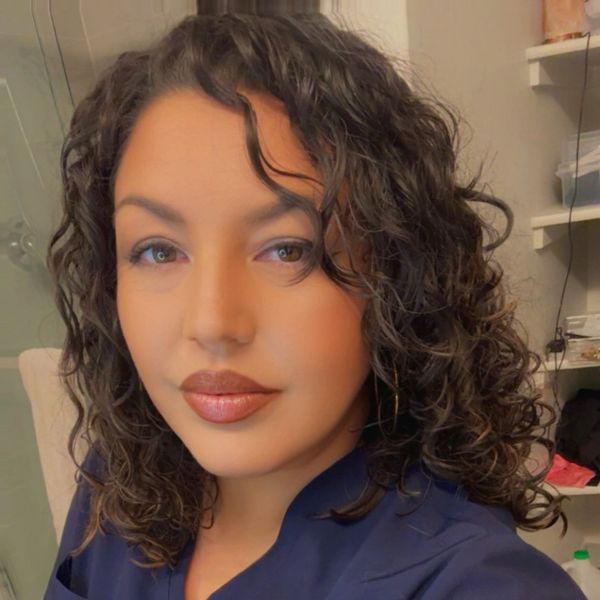 A woman with curly hair and a calm expression in a casual setting.