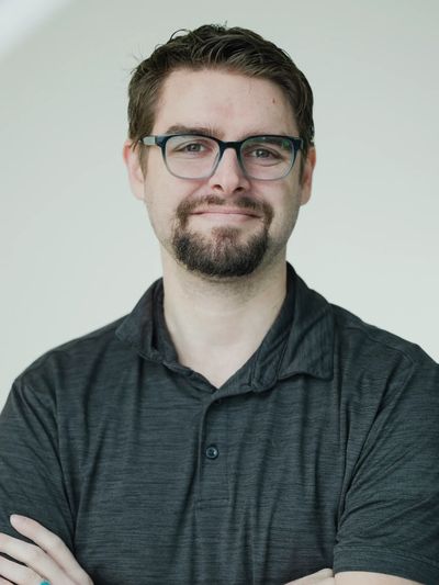 Man with glasses and facial hair smiling.