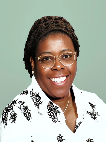 Smiling woman with glasses and braided hair against a green background.