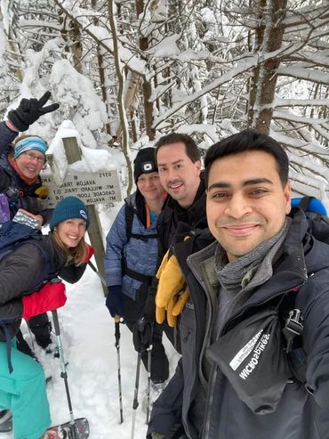 Hikers on a snowy mountain surrounded by trees