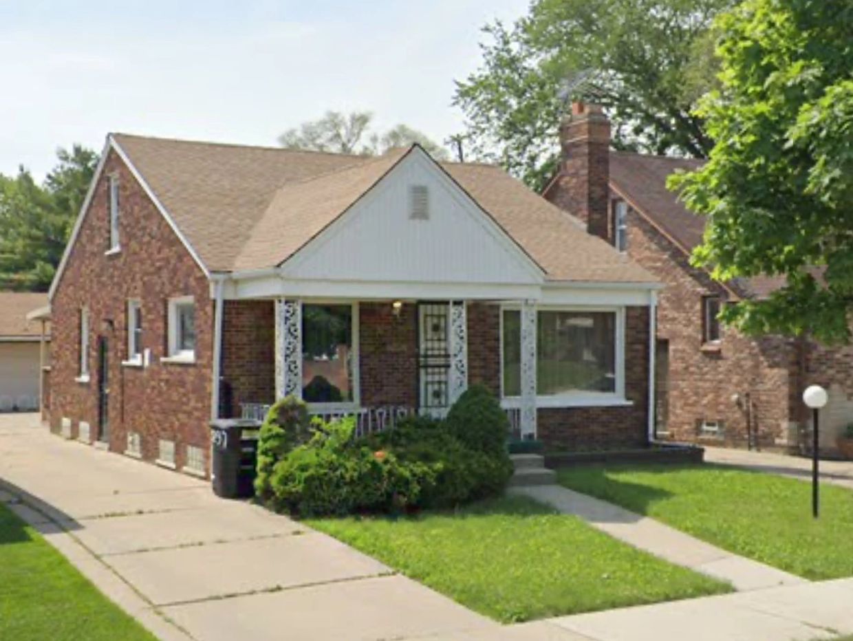 Brick single-story house with a small front porch and greenery.
