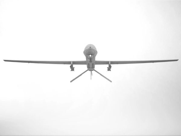 Front view of a drone flying against a bright sky.