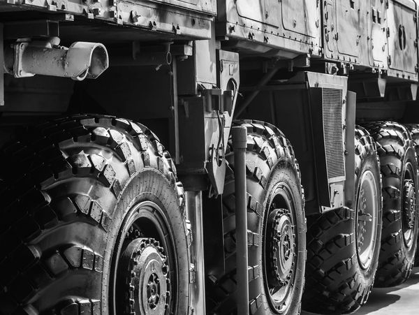 Close-up of large, rugged tires on a heavy military vehicle in black and white.