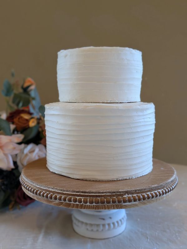 6-inch 3-layer cake on 8-inch 3-layer cake, vanilla textured frosting over plastic cake boards