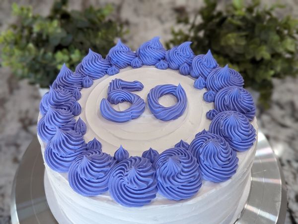 8-inch cake, vanilla textured frosting, large purple swirl top border with star accents