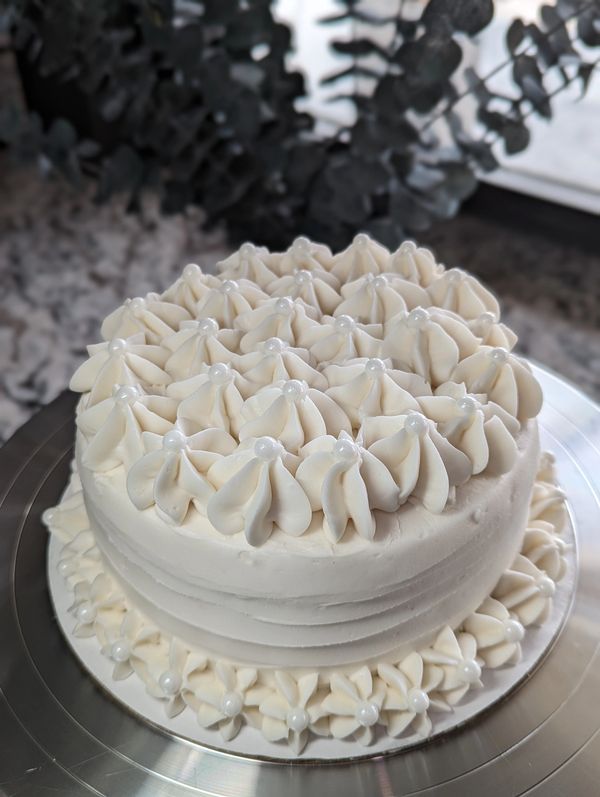 6-inch cake, vanilla textured frosting, flowered top, flower bottom border, large pearls
