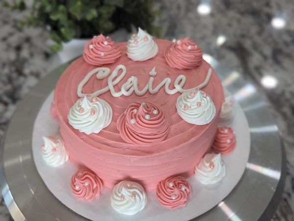 6-inch cake, vanilla textured frosting in pink, large pink and white swirls spaced on top and bottom