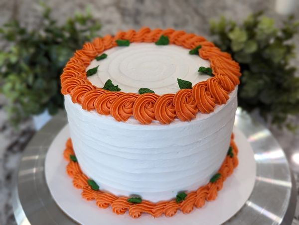 6-inch (3 layer) carrot cake, vanilla textured frosting, orange wrapping swirl border, green leaves