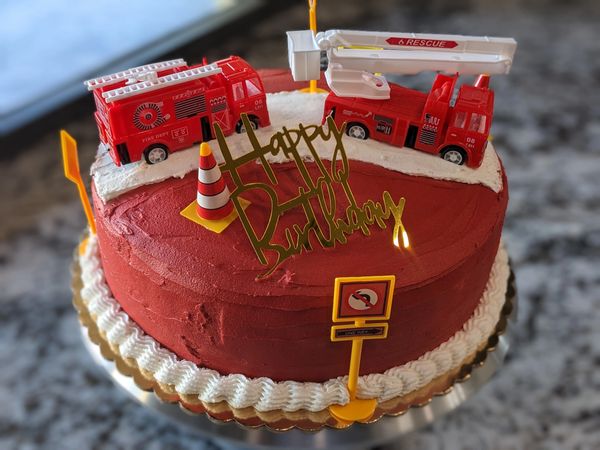 10-inch fire truck cake, vanilla textured red frosting, white flat "street," bottom border