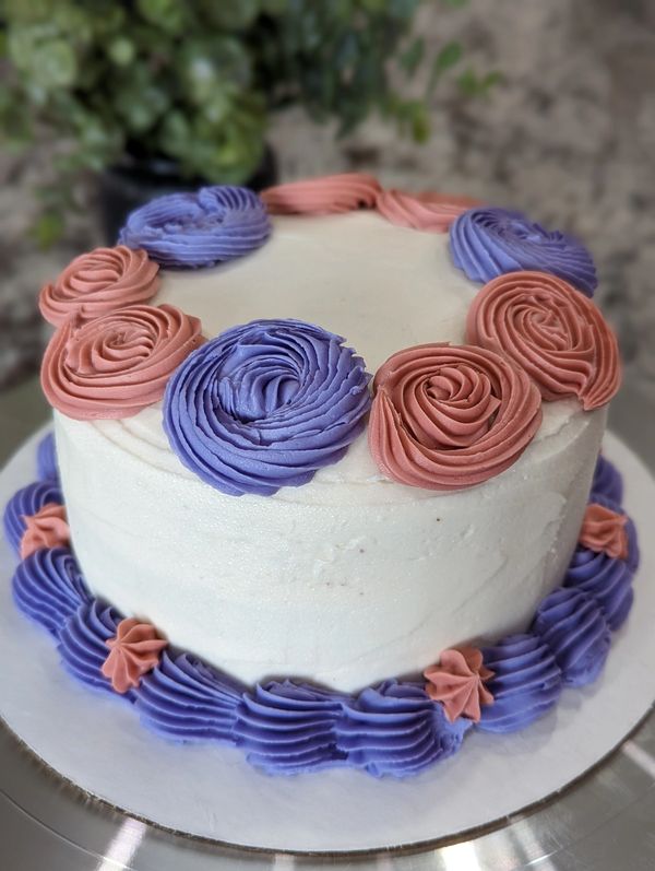 6-inch cake, vanilla flat frosting, pink and purple rosettes top border, shell bottom border