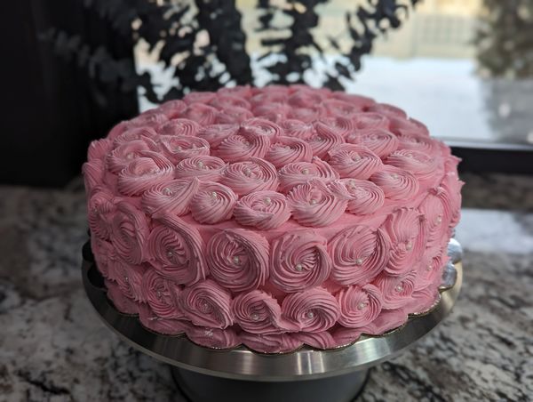 10-inch cake, vanilla frosting in pink rosettes covering top and sides, white pearl accents