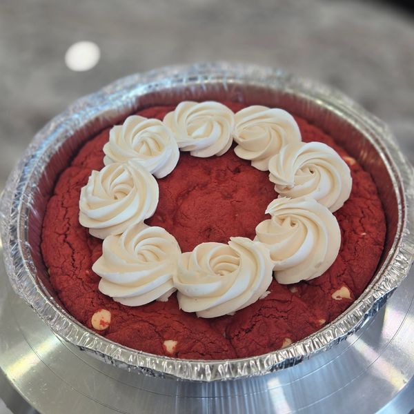 8 inch red velvet pizookie with white chocolate chips, vanilla frosting rosettes on top